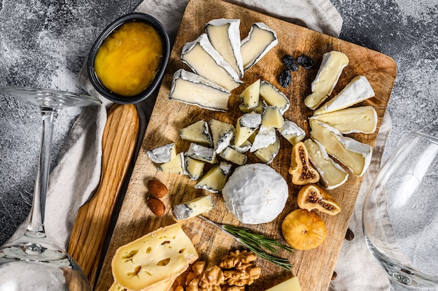 Cheese plate served with nuts and figs. Italian antipasto. Gray background. Top view.