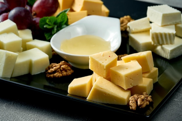 Cheese plate with different types Concrete background Assorted cheeses for an appetizer in a black plate