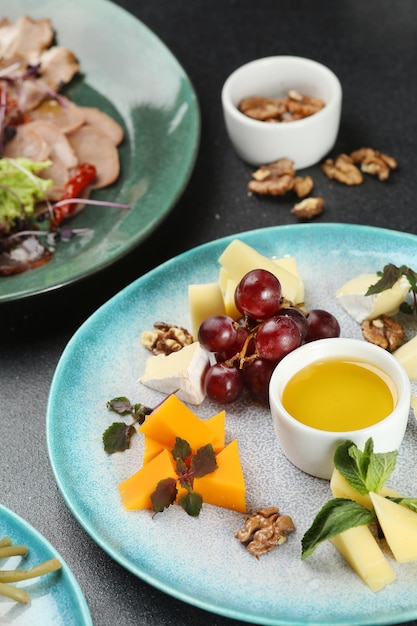 Cheese plate with honey and grape on dark concrete table. dinner concept.