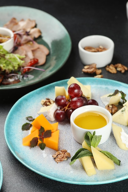 Cheese plate with honey and grape on dark concrete table. dinner concept.