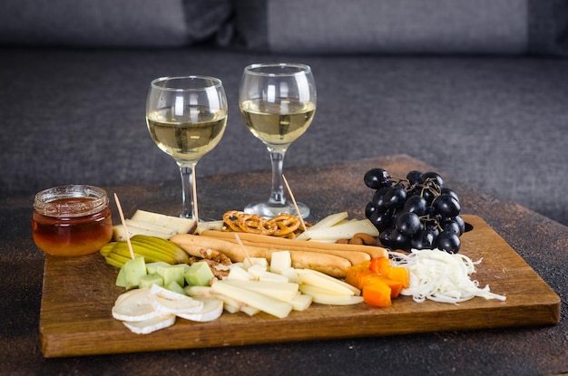 Cheese plates served with grapes jam snacks crackers and nuts on a wooden board