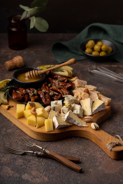 Cheese platter with different cheeses, dried tomatoes, nuts, honey and dates.