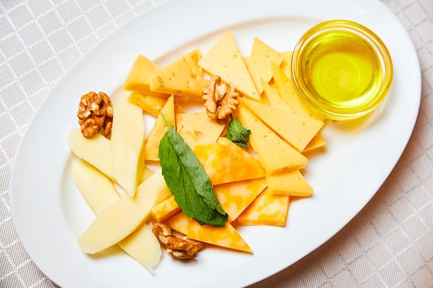 Cheese platter with honey and walnuts on a white plate