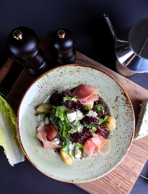 Cheese salad with greens dried ham in vintage plate