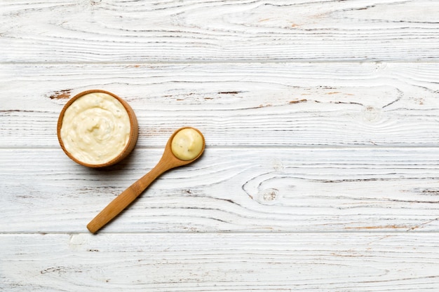 Cheese sauce in wooden bowl with spoon on wood background Top view with copy space