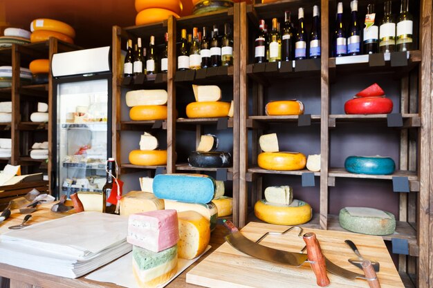 Cheese shop interior, showcase with shelves. Assortment of cheese wheels in store