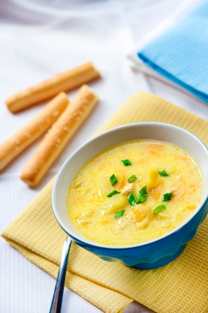 Cheese soup with chicken, potatoes and turmeric with grissini on a background