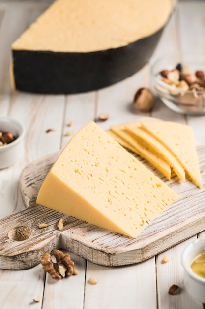 Cheese with the aroma of melted cream and walnut on a wooden board. Dark wooden background. Side view close-up.