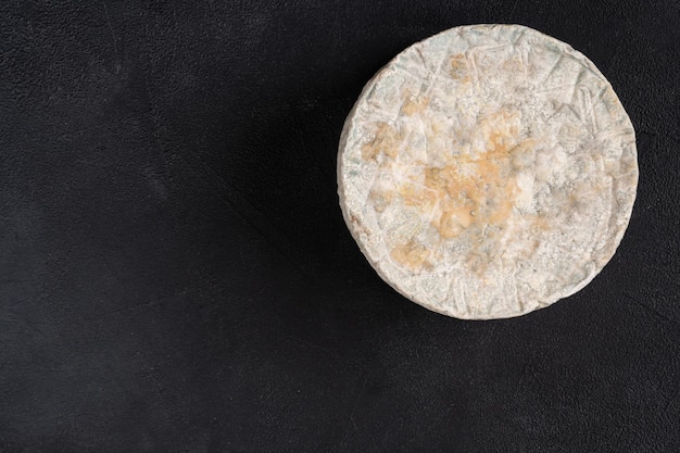 Cheese with blue mold. Top view on a black background.