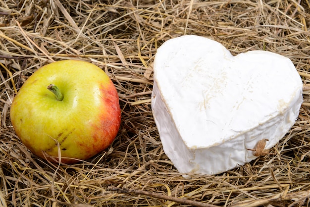 Cheese with heart shape and an apple on straw