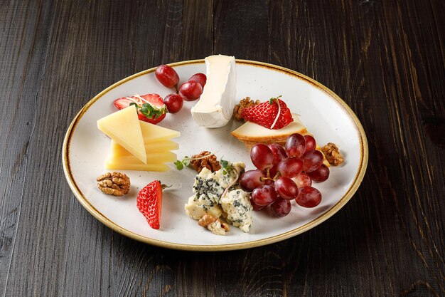 Cheese with strawberries and nuts on plate