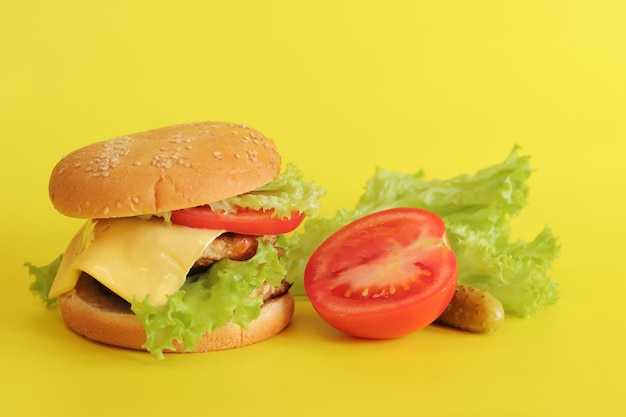 Cheeseburger and fresh vegetables on a yellow background