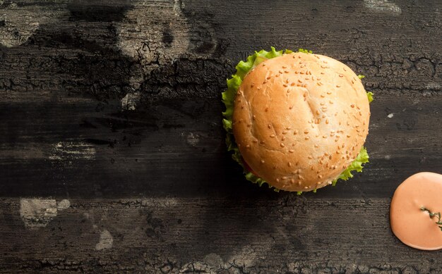 Cheeseburger on an old wooden surface of dark color hamburger with sauce and ketchup