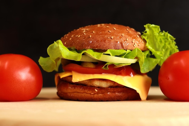 Cheeseburger with chicken cutlet closeup. Fast food on a dark background