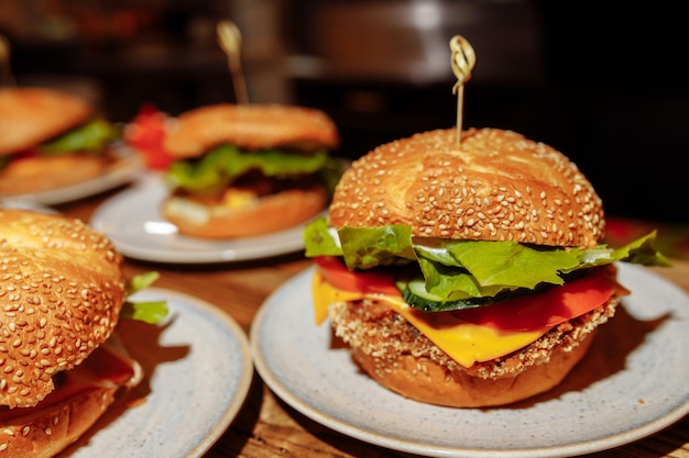 Cheeseburgers and fries on table top with onion, tomato, lettuce and cheese