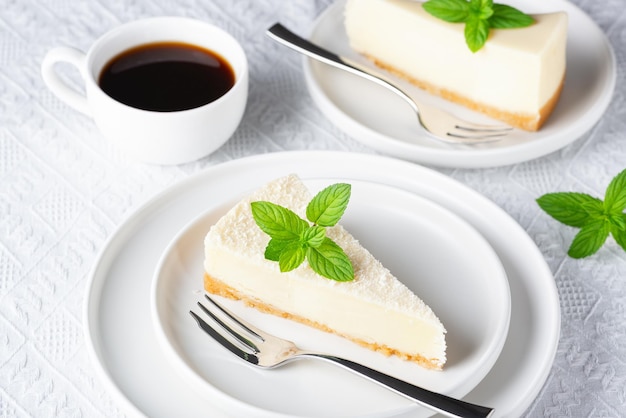 Cheesecake and cup of black coffee on a white table