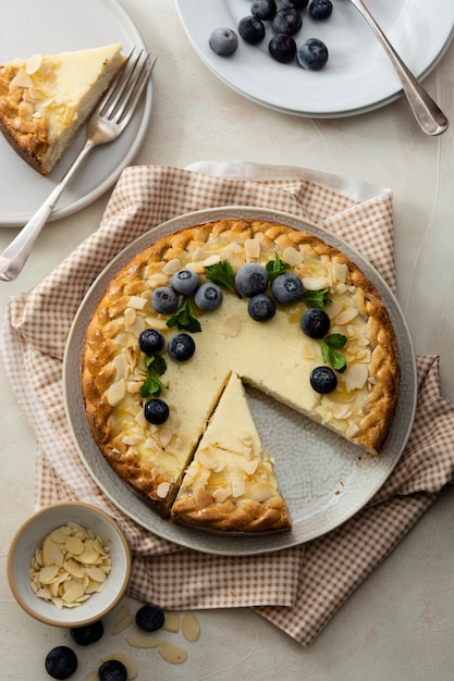 Cheesecake slice with blueberry and almond flakes with cutlery on a light background top view