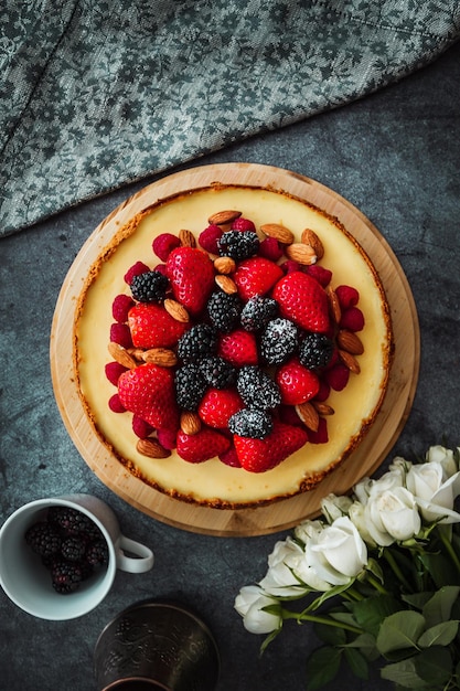 Cheesecake with berries on the concrete background with napkin and flowers