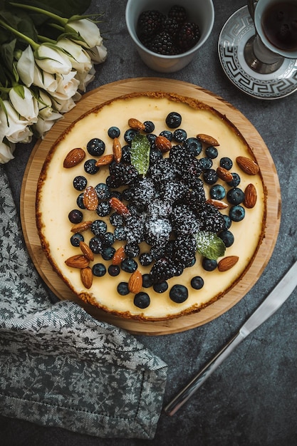 Cheesecake with blackberries almond strawberries on the concrete background with napkin