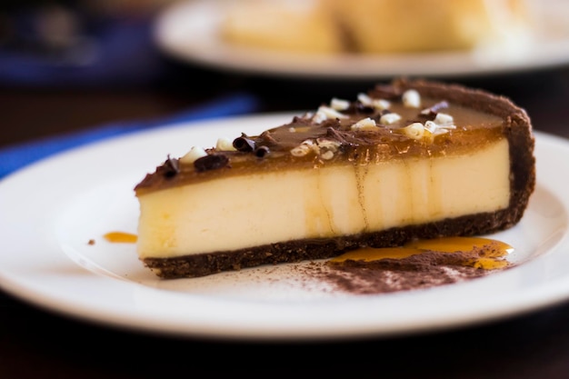 Cheesecake with caramel and chocolate topping on a white plate