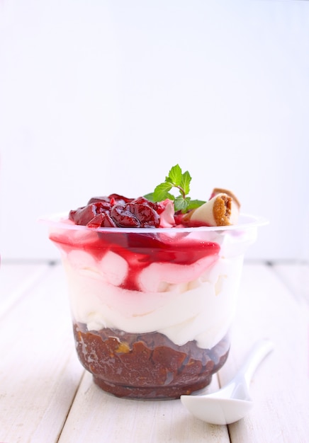 Cheesecake with a cherry in a glass decorated with mint on a white background