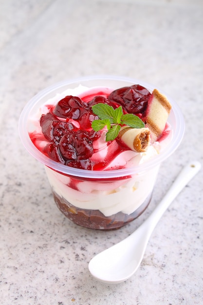 Cheesecake with a cherry in a glass decorated with mint on a white background