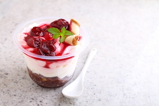 Cheesecake with a cherry in a glass decorated with mint on a white background