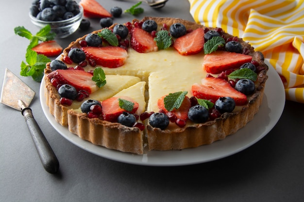 Cheesecake with fresh berries and mint for dessert. Gray background.