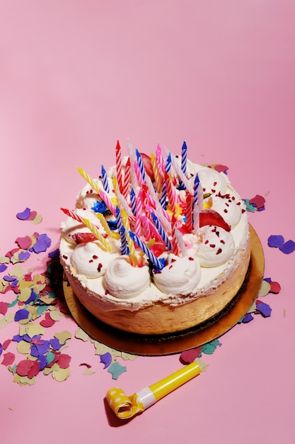 Cheesecake with lots of birthday candles and confetti on a pink background