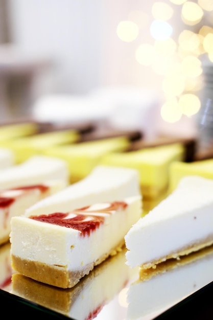 Cheesecakes on a mirror tray stand on a buffet table against the background of golden bokeh