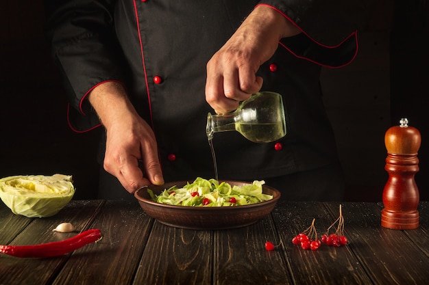 The chef adds oil to a fresh vegetable salad