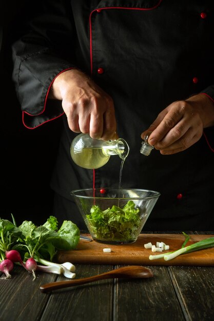 The chef adds olive oil to a vegetable salad Vegetarian food by cook hands in the kitchen Vegan menu idea for hotel or restaurant