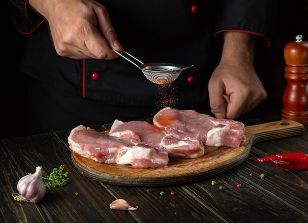 The chef adds paprika to raw meat ribs before grilling