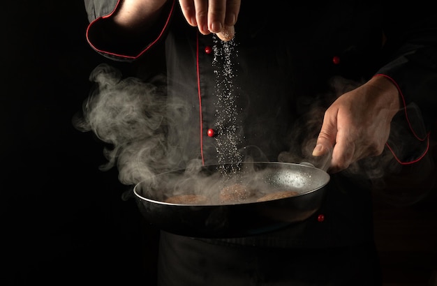 The chef adds salt to cutlets that are fried in a pan Cooking meat patties for a burger