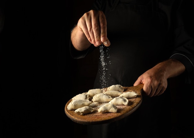 The chef adds salt to meat dumplings on a cutting board