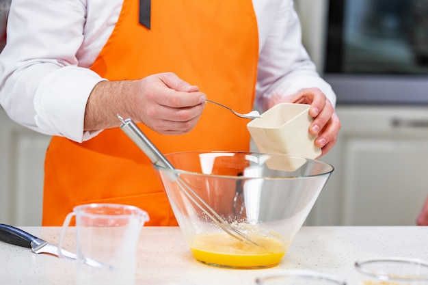 chef adds sugar to the beaten eggs