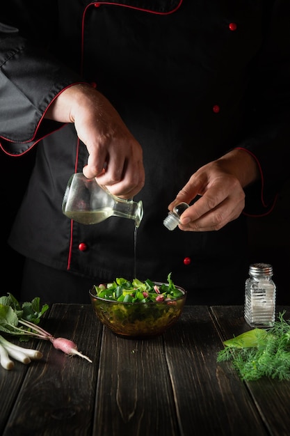 The chef adds vegetable oil to a fresh Lettuce salad Preparing a vegetarian breakfast in the kitchen