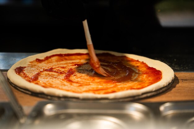 Chef Applying Sauce to Pizza Base