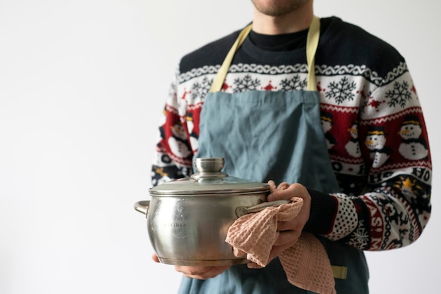 A chef in apron cooking dish holding a pot in the kitchen