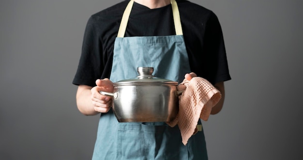 A chef in apron cooking dish holding a pot in the kitchen