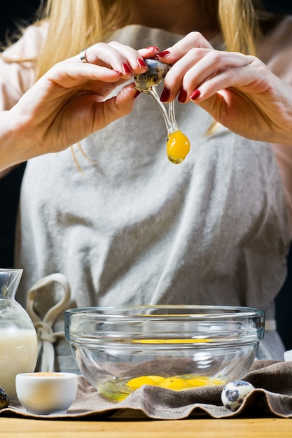 The chef breaks a quail egg into a bowl. 