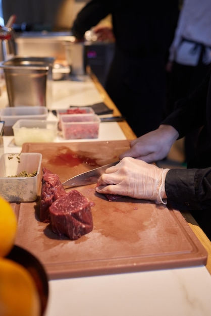 Chef Butcher cutting pork meat with knife on kitchen cooking food