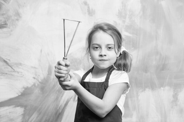 Photo chef child with masher for potato kid in cook apron cooking with kitchen tool childhood and education small girl on colorful background