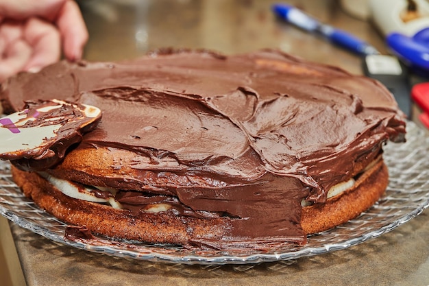 Chef coats the cake with chocolate ganache to make chocolate cake with pears and walnuts