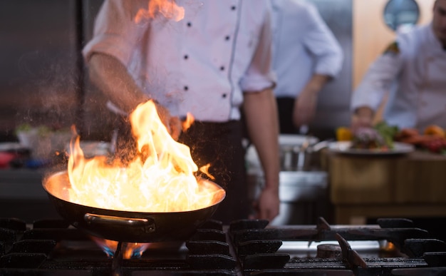 Chef cooking and doing flambe on food in restaurant kitchen