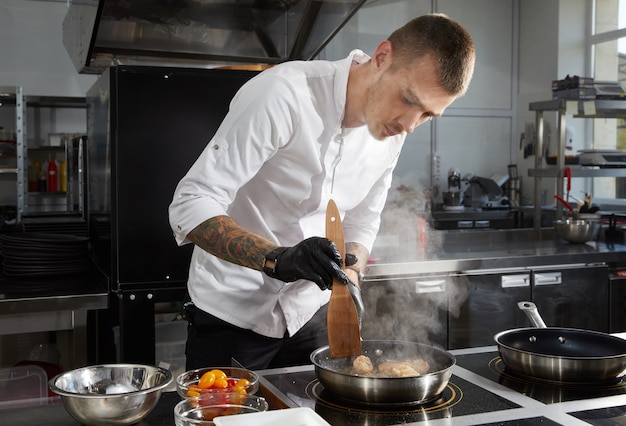 Chef cooking in the modern kitchen in hotel restaurant preparing shrimp salad