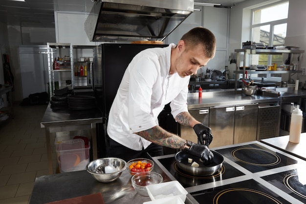 Chef cooking in the modern kitchen in hotel restaurant preparing shrimp salad