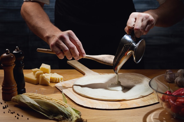 Chef cooking pizza, putting white sauce on pizza base