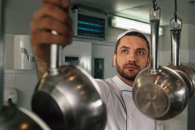 Chef cooking tasty dish in kitchen of restaurant using modern equipment