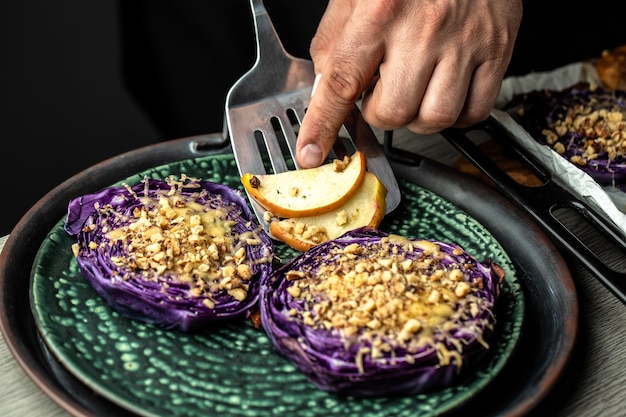 Chef cooking traditional German dish of red cabbage baked with nuts quince and apples Vegan roasted red cabbage steaks Food recipe background